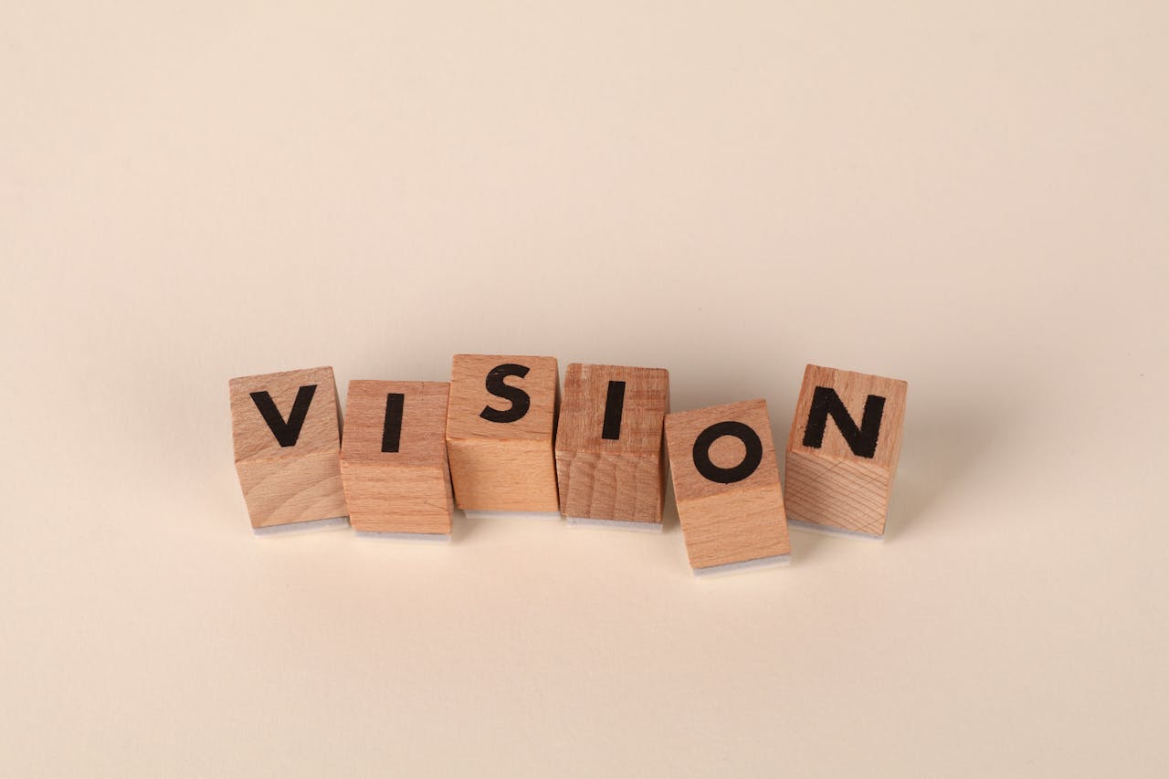 Wooden blocks with black letters spelling VISION on a light beige background, symbolizing foresight and goals.